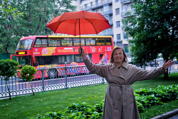 A woman with a red umbrella at a tourist bus in Moscow, Russia