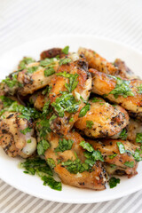 Homemade baked Garlic Parmesan Chicken Wings on a white plate, side view. Close-up.