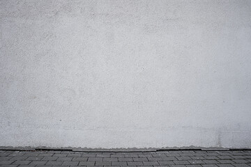 Large empty gray wall of urban building over tiled sidewalk at city street