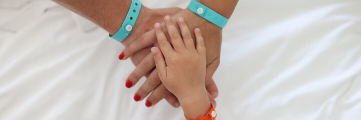 Bracelets are worn on child and an adult hand and they are folded together