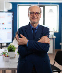 Portrait of succesful senior entrrepeneur in conference room smiling at camera with arms crossed. Manager working in professional start up financial business, modern company workplace ready for