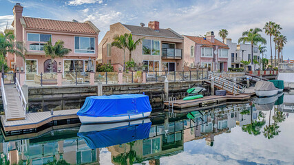 Fototapeta na wymiar Pano Blue sky and clouds reflected on water of canal bordered by houses and docks