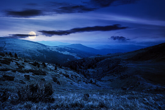 carpathian mountain landscape at night. beatiful scenery with green rolling hills in full moon light beneath a clouds on a dark sky in summer. popular travel destination of chornohora ridge