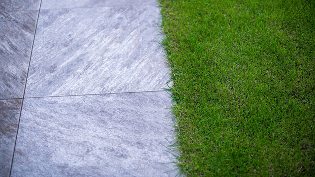 Perfekter gr&uuml;ner Rasen neben grauen Terrassenplatten