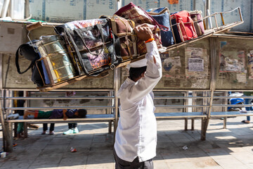 Mumbai, India, 18 november, 2019. Dabbawala lunchbox delivery service: operators with typical white hat delivering lunchboxes with warm homemade food. Operators transporting the lunchboxes.