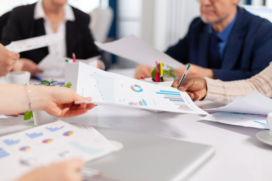 Close up of diverse startup company colleagues meeting in professional workplace, brifing and sharing ideas over financial strategy. Colleagues working in office at conference table in startup