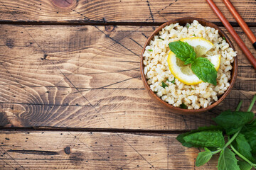 Boiled bulgur with fresh lemon and mint on a plate. A traditional oriental dish called Tabouleh. wooden background rustic top view, copy space