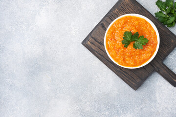 Homemade caviar from zucchini tomatoes and onions in a ceramic plate, on a gray background. Homemade production canning, canned stewed vegetable. top view, copy space