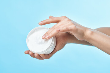 jar of cream in hand skin care close-up cosmetics blue background