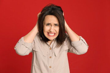 Portrait of angry woman on red background. Hate concept