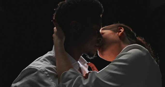 Love couple of two separate nationalities, dark skinned man almost kissing beautiful woman, fascination, flirtation, hookup, romantic scene in twilight on dark background