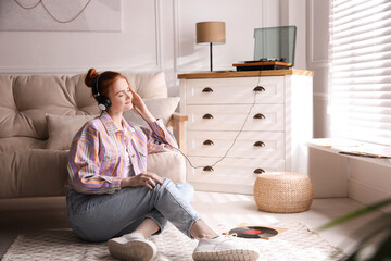 Young woman listening to music with turntable in living room