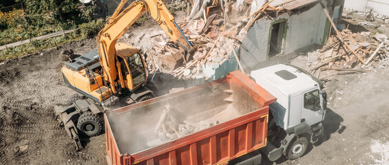 Excavator loads construction debris of old building after destruction in dump truck, aerial view...