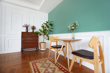 테이불과 의자, 그리고 그린벽과 우드 바닥이 있는 리빙룸