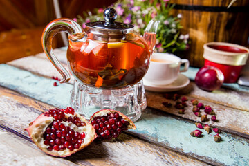 red fruit tea in a teapot with pomegranate on the table