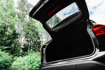 Modern black car with open trunk door on road. - obrazy, fototapety, plakaty