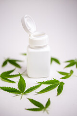 Obraz na płótnie Canvas cannabis leaves and a jar for medical preparations on a white background