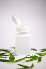 white medical jar and marijuana leaves on a white background