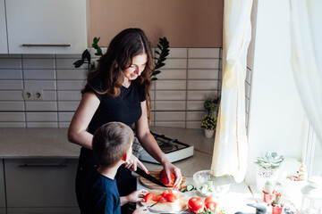 mother and son prepare a salad of vegetables in the kitchen