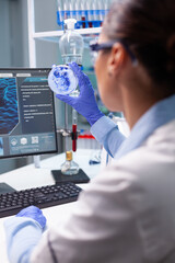 Biologist woman looking at bacteria virus using medical petri dish working at genetic infection...