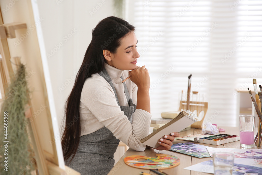 Poster Young woman drawing in notebook at table indoors