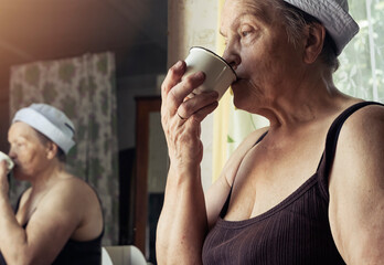 Tired mature real female farmer drinking water from mug and looking sad. Portrait of candid woman