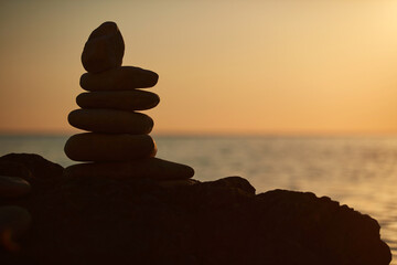 Fototapeta na wymiar Zen stones on a ocean sea cliff in sunset sunrise time.