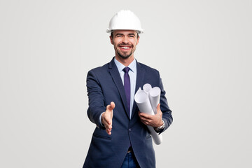 Smiling engineer with blueprints outstretching hand to camera