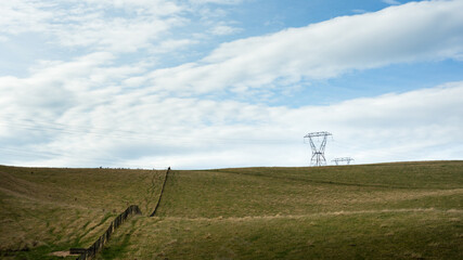 High voltage transmission towers and overhead powerlines against the cloudy sky on Desert road, North Island.