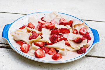 Russian food, pasta with strawberries called vareniki or warenike. Sweet traditional summer meal.