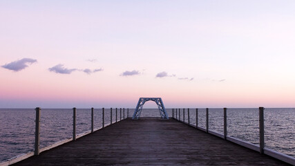 Obraz premium Small copy in construction of the famous Eiffel Tower on end of pier in Yalta, Crimea at sunset, Russia