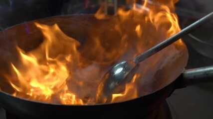 Asian style of cooking food on fire. the chef stir the noodles on in a burning bowl. wok noodles