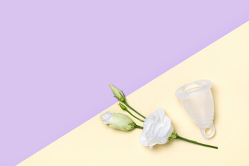 Reusable menstrual cup and tender white flower Eustoma on pastel yellow and purple background. Women health concept, zero waste feminine hygiene product, eco-friendly alternative for pads or tampons