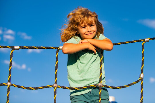 Child Climbing On Climbing Frame In Park On Summer Day, Having Fun Smiling Outdoors. Kids Enjoying Playing Activities, Leisure Recreation Lifestyle.