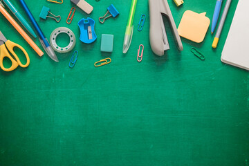 Welcome to school. Office supplies on a green school board. Various school supplies on a shabby green background. Text frame with stationery. School layout. Sale concept