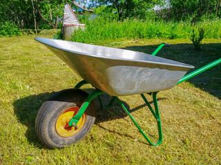Green vegetable garden. Lawn. Mown grass. Garden wheelbarrow. Gardening Tools. Close-up.