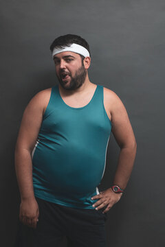 
young fat man posing on a gray background while making funny face.