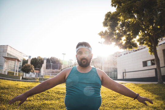 young fat man warming up in an outdoor park.
angle view.
willpower.