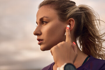Woman using earbuds during outdoor workout - obrazy, fototapety, plakaty
