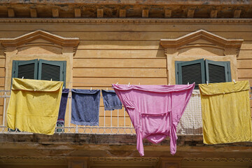 clothes drying in the sun and facade of typical rustic italian tenement