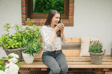 Beautiful woman is drinking tea in the garden next to flowers and plants.
Garden joy in summer....