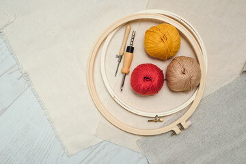 Round stretching frames, punch needles, balls of yarn and three different types of fabric layout on...
