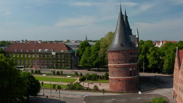 Rise up footage of historic centre of city. Aerial side view of Holsten Gate. Brick Gothic relic of medieval city fortification. Luebeck, Schleswig-Holstein, Germany