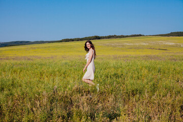 a beautiful woman in a dress walking in a field in nature