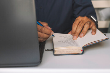 Unrecognizable mature man writing notes while working in home office.
Business conceptual