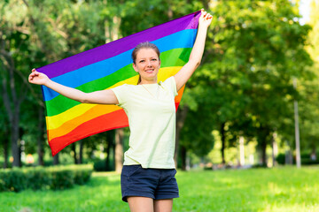 Portrait of young lesbian happy proud woman, beautiful girl is waving rainbow LGBT color gay flag...