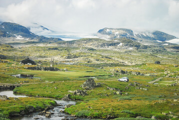 Fototapeta na wymiar Panorama view of the scenic alpine meadow of Norway with glacier, stream, cottage house and a car