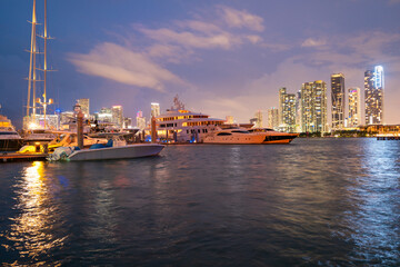 Fototapeta premium Miami, Florida cityscape skyline on Biscayne Bay. Panorama at dusk with urban skyscrapers and bridge over sea with reflection.