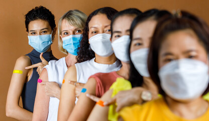 Diverse group of multinational ethnic female patients wears face mask stand in line by height order...