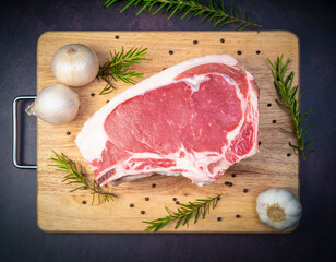 Raw fresh Rib eye steak beef with herbs on wooden background, Close-up view of marble Rib eye steak beef for steak on wooden plate.